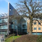The Swansea University campus main building. This picture was taken on a bright clear day with students walking past the front.